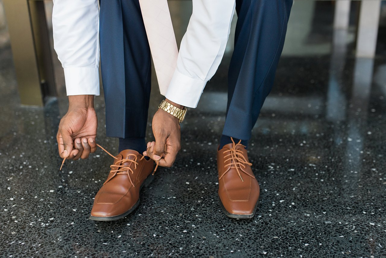 Groom getting dressed, tying brown leather shoes